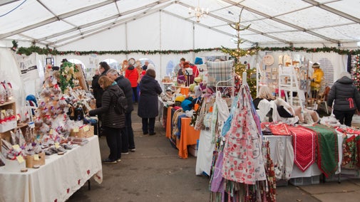 Visitors browsing stalls at a Christmas Market in a marquee